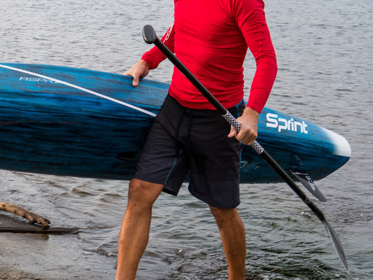 Paddler carrying a blue SUP and a paddle fitted with white RSPro Paddle Grip Hexa
