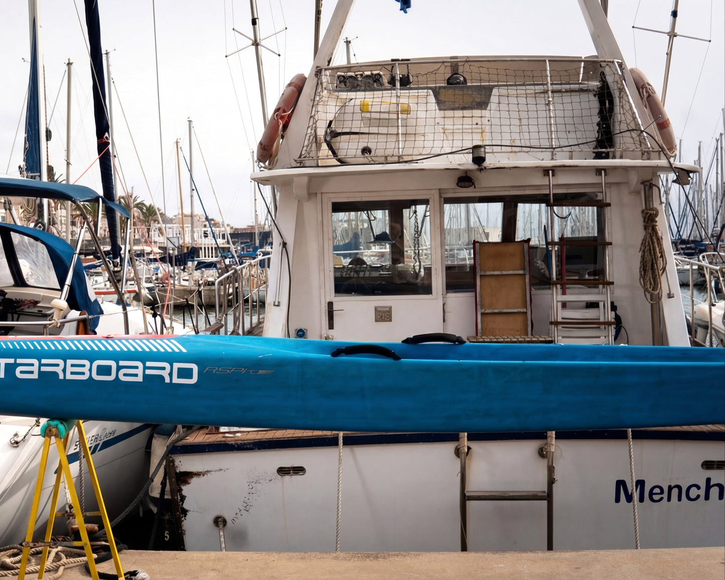 Blue Starboard SUP board on a dock with boats in the background